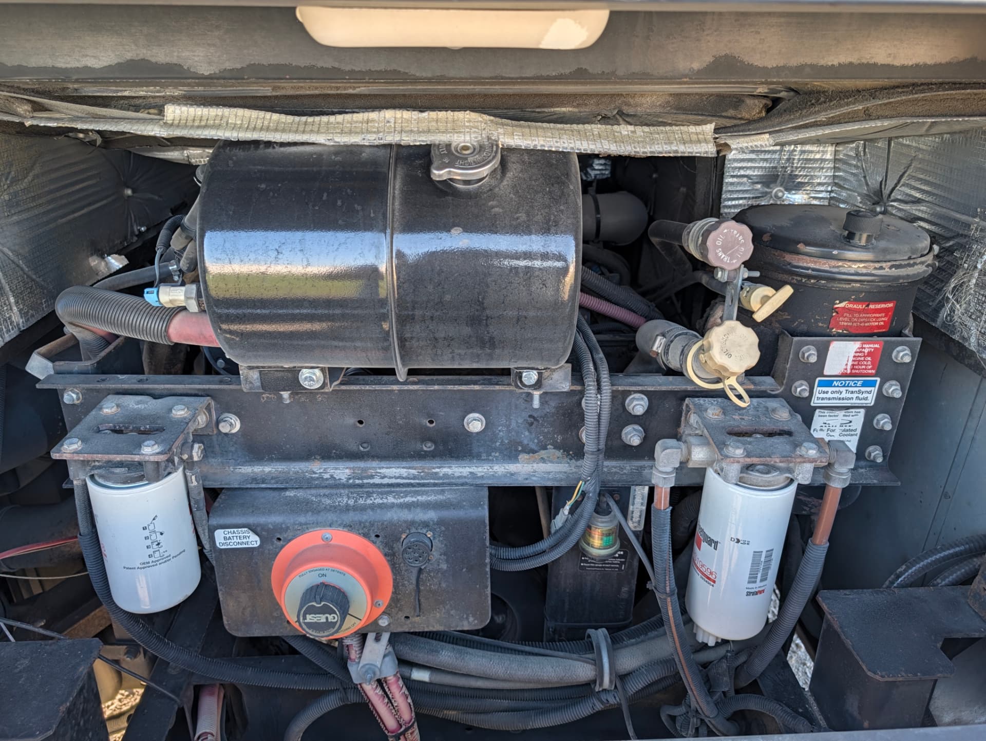 Open rear engine compartment showing coolant tank, filters and chassis battery disconnect