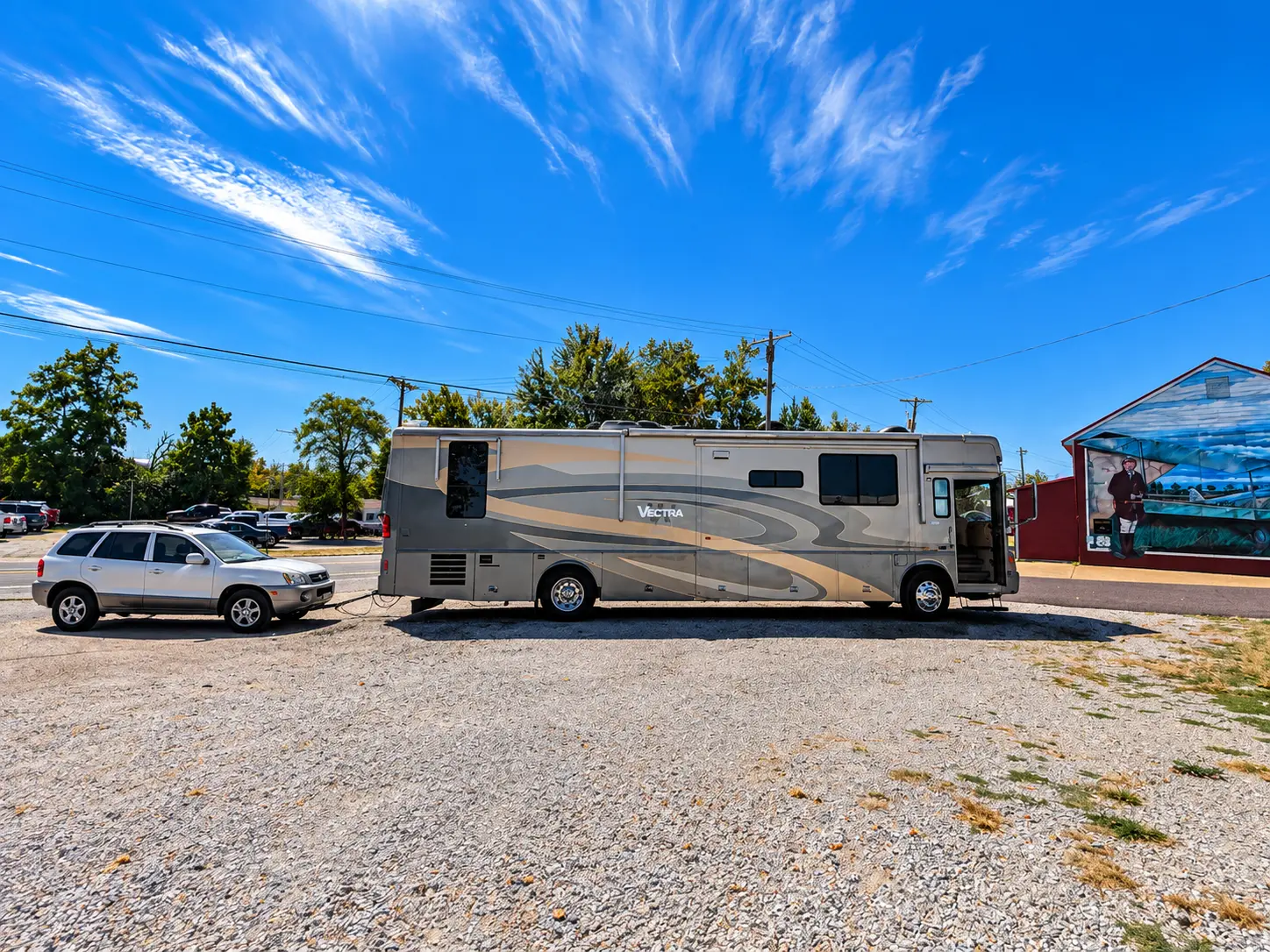 Winnebago Vectra towing the Hyundai Santa Fe, parked by a mural on Route 66