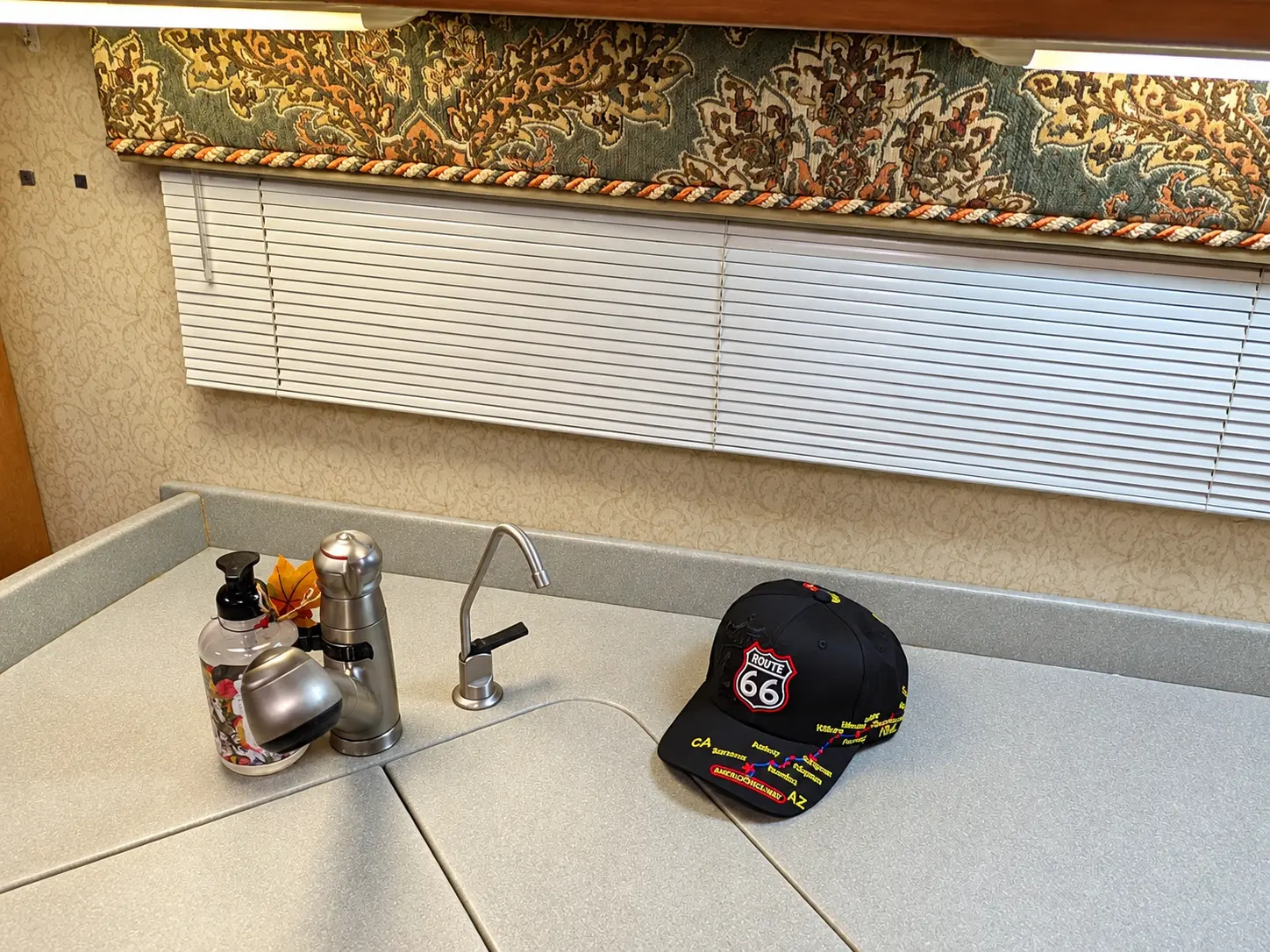 A black Route 66 highway baseball cap resting on the covered kitchen sink inside the coach