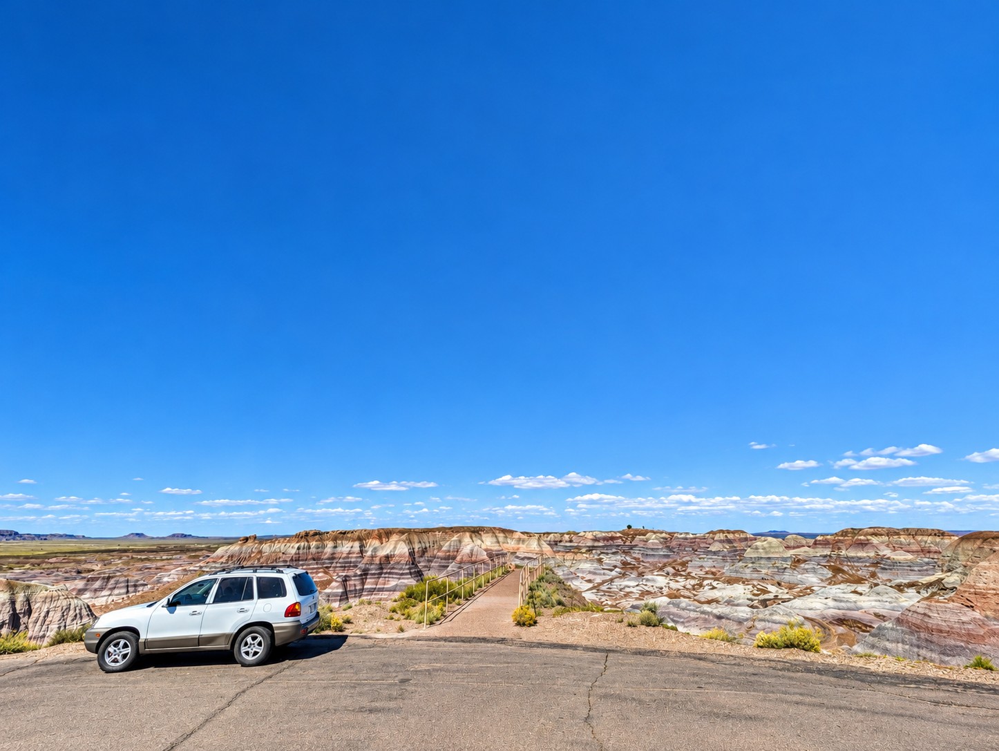 White Hyundai Santa Fe parked at an overlook above colorful desert badlands