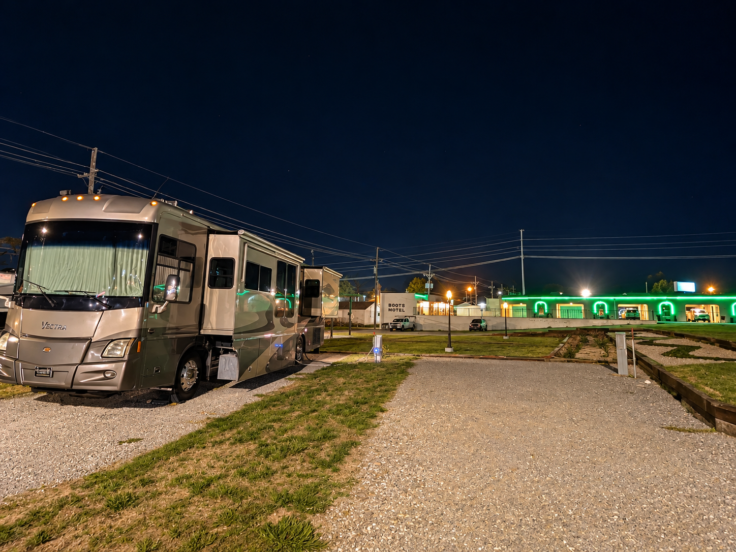 The Vectra parked and plugged in for the night in front of the Boots Motel, its carport bays outlined in green neon