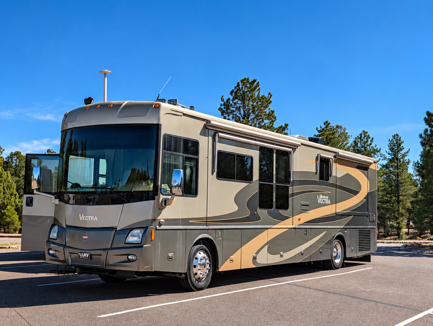 2007 Winnebago Vectra front passenger-side view parked among trees with slides retracted