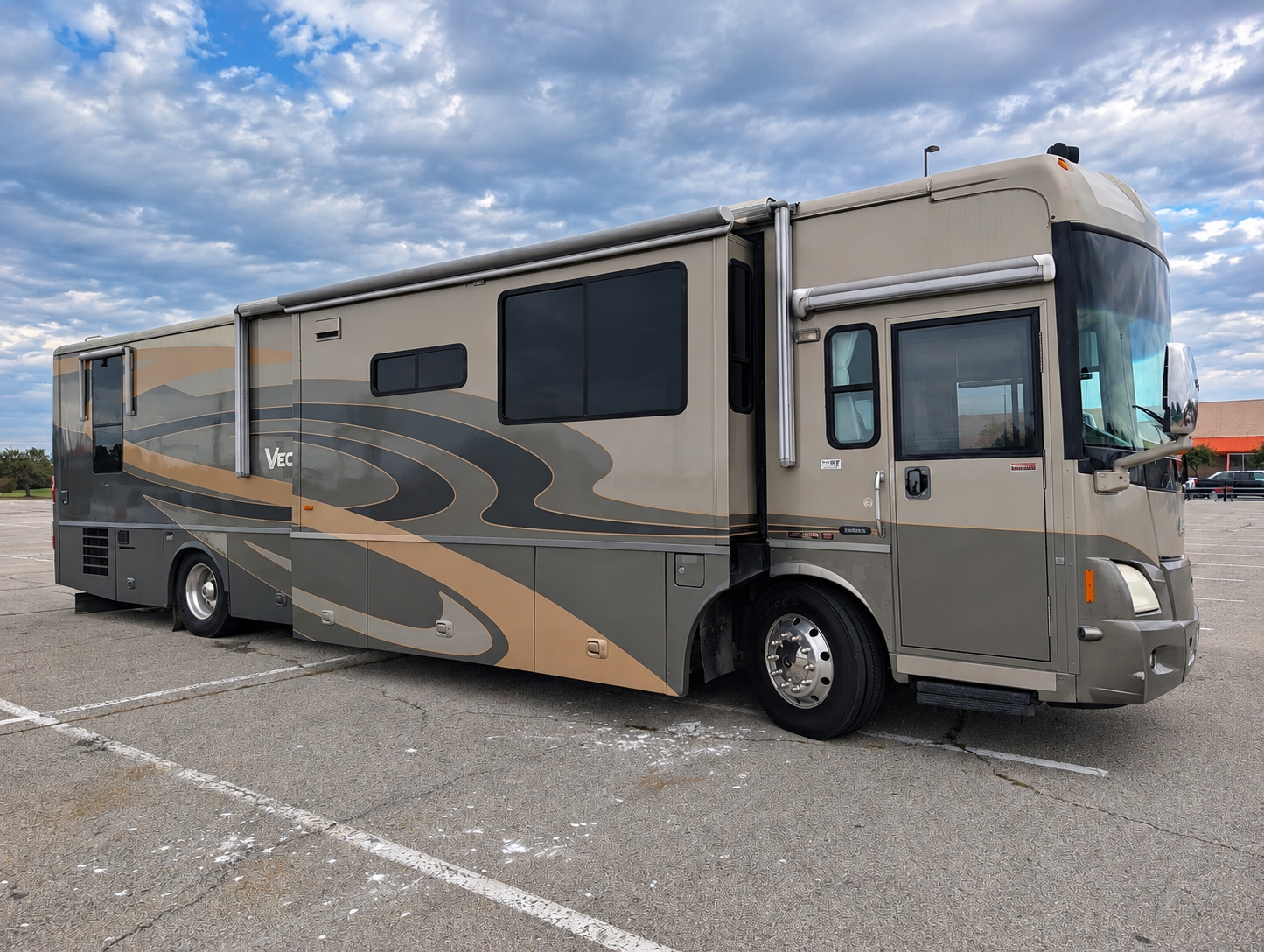 Winnebago Vectra passenger side view with the entry door and awnings