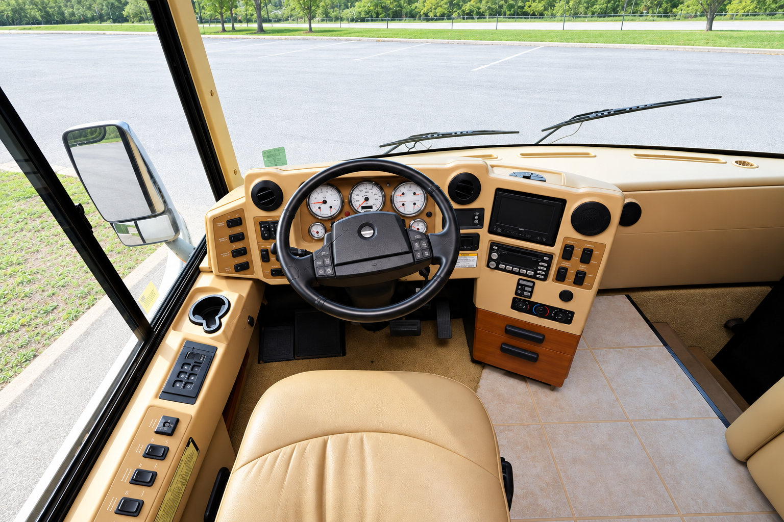 View from the driver's seat of a 2007 Winnebago Vectra showing the one-piece windshield, instrument dash and tan leather seat